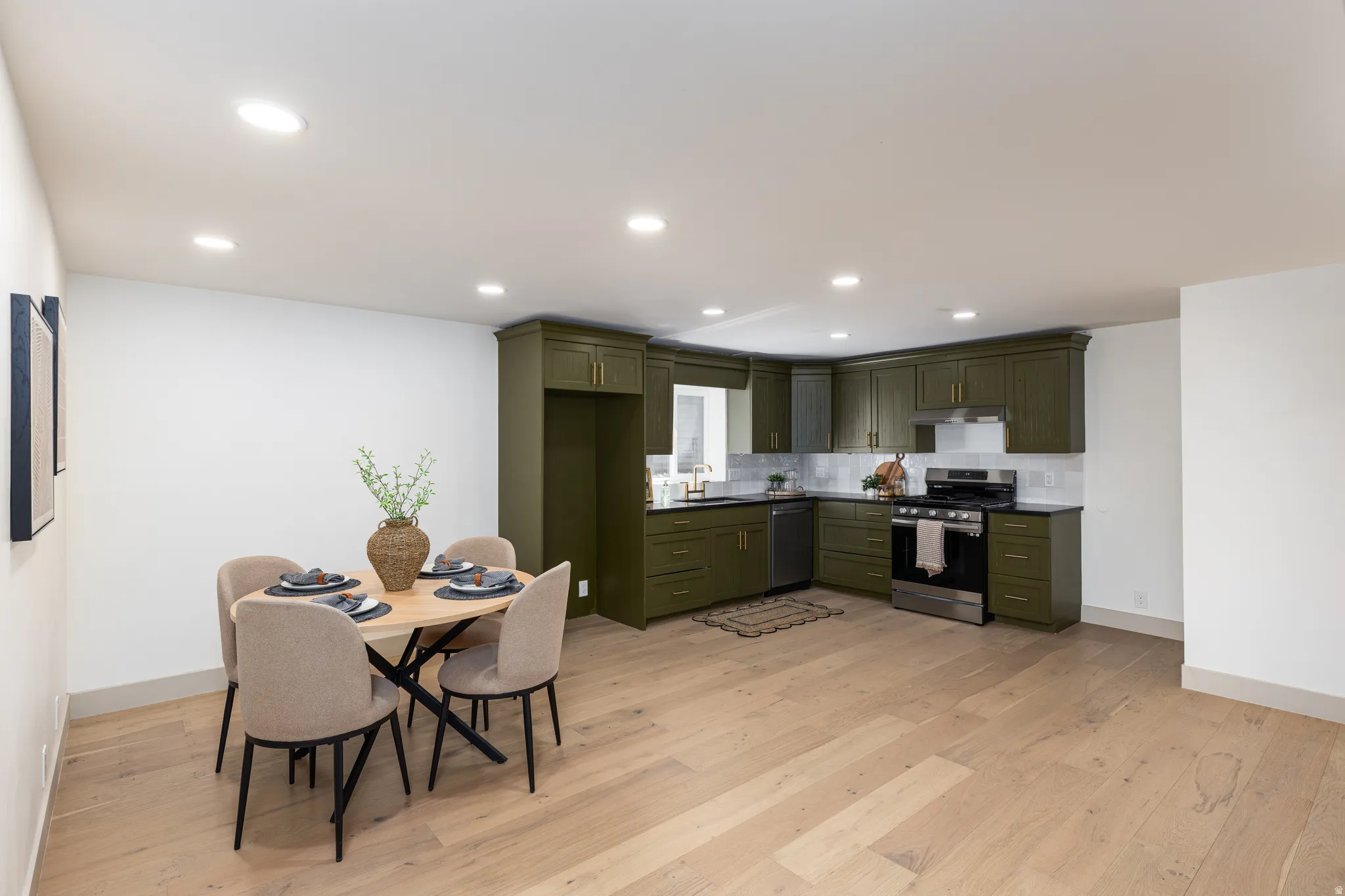 Open-concept living space with light wood-finish flooring, recessed lighting, and white walls