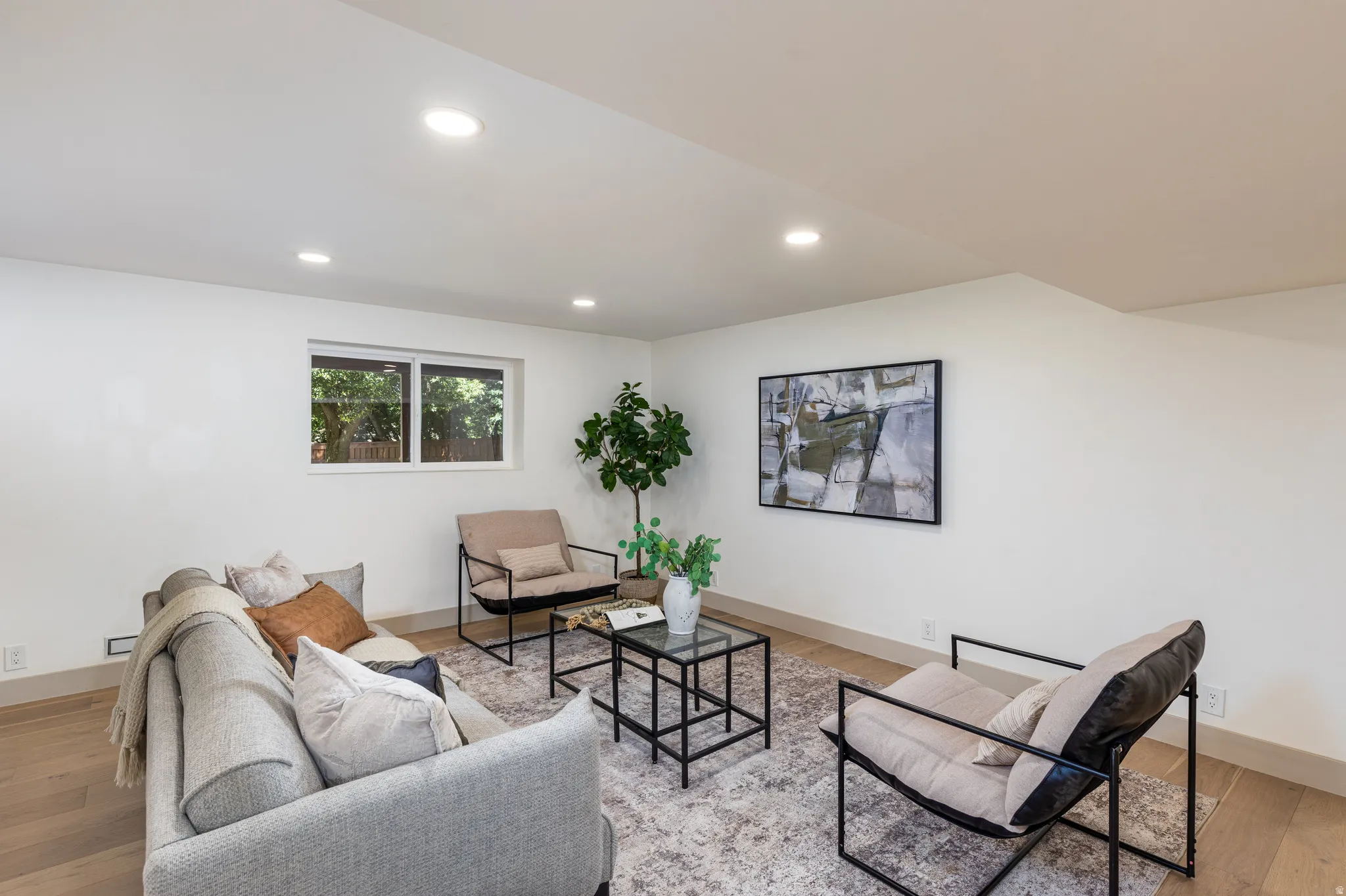 Bright living area featuring recessed lighting, light wood-finish flooring, a contemporary window, and clean white walls
