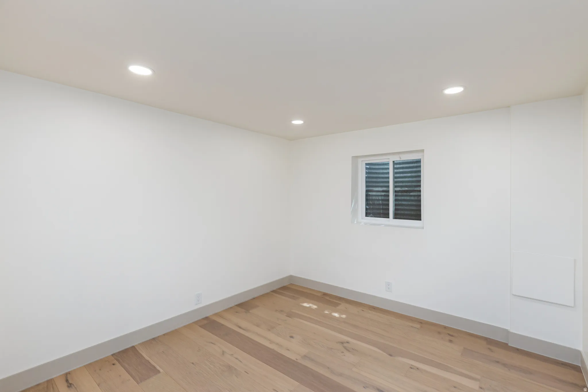 Room featuring wood-finish flooring, recessed lighting, and a white window with horizontal blinds