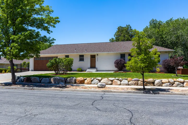 Ranch-style residence featuring a wood-finish garage door, a light-colored exterior, and a front entry door with side windows