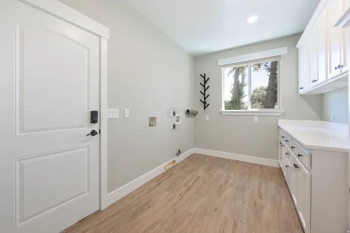 Upstairs Laundry with Wood-finish flooring, white cabinetry, a single window, and recessed lighting. Hookup for 2 washers and 2 dryers (gas or electric)