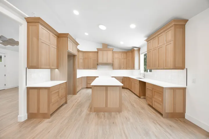 Large open Kitchen featuring light oak wood cabinetry, a large island, and top of the line LVP flooring. A luxury stove and dishwasher will be installed before closing