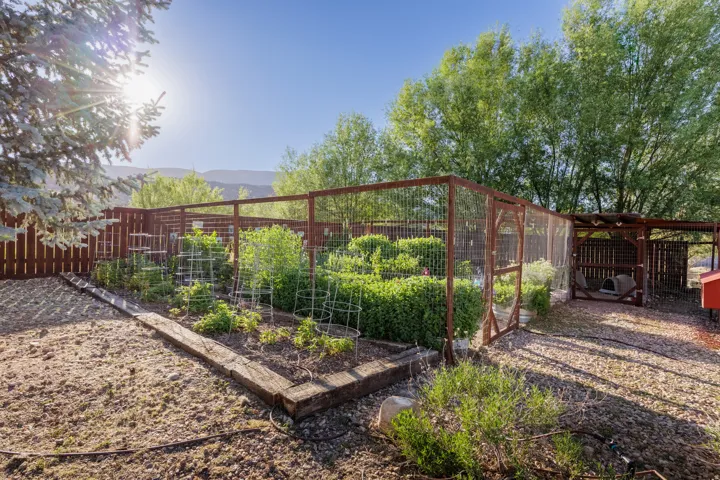 Fenced garden area featuring multiple raised beds and an enclosed structure