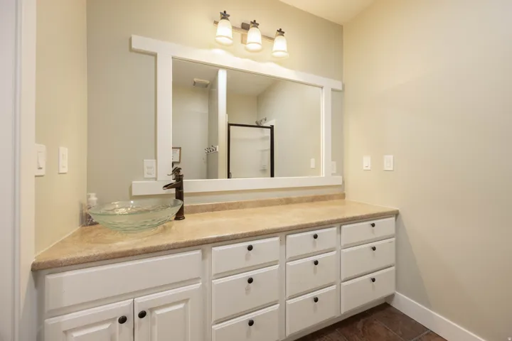 Basement Bathroom vanity with a vessel sink, dark bronze faucet, and ample cabinetry