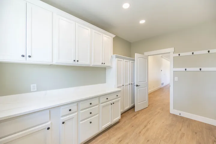 Upstairs Laundry with Wood-finish flooring, white cabinetry, a single window, and recessed lighting. Hookup for 2 washers and 2 dryers (gas or electric)