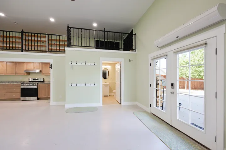 Open concept interior featuring high ceilings and a second-story loft with black wrought iron railing