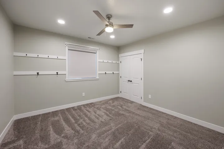 Carpeted interior space featuring a ceiling fan with integrated lighting, recessed ceiling lights, and large closet