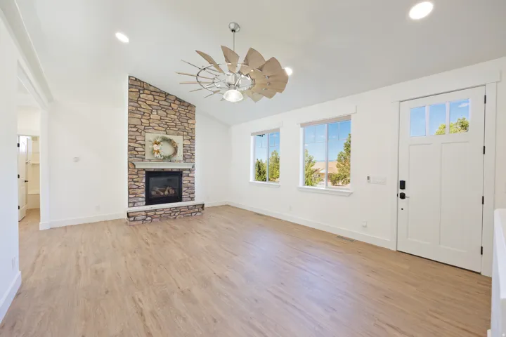 Living space featuring a stone-clad fireplace with a hearth, vaulted ceilings, and light wood-finish flooring