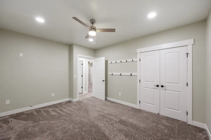 Carpeted interior space featuring a ceiling fan with integrated lighting, recessed ceiling lights, and large closet