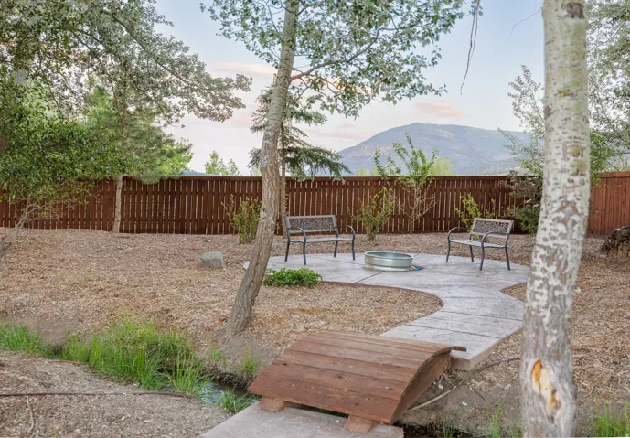 Backyard featuring a fire pit, concrete patio, wooden privacy fencing, and mature trees