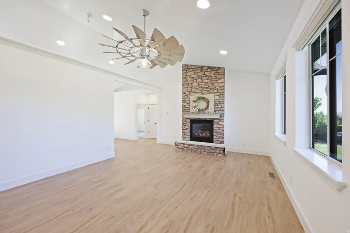 Living area featuring a stone-clad fireplace with a hearth, wood-finish flooring, and recessed lighting