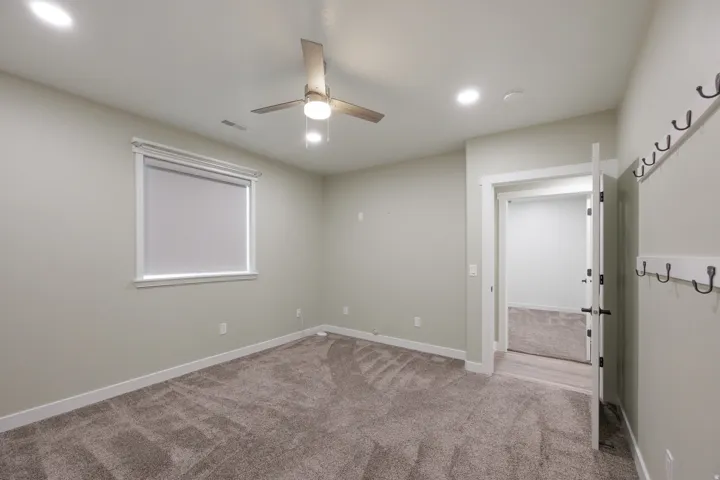 Carpeted interior space featuring a ceiling fan with integrated lighting, recessed ceiling lights, and large closet