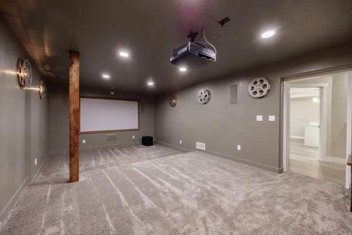 Dedicated media room featuring a ceiling-mounted projector, recessed lighting, and a large projection screen