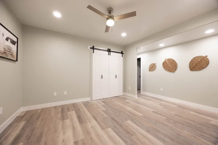 Wood-finish flooring, recessed lighting, ceiling fan, and white barn doors