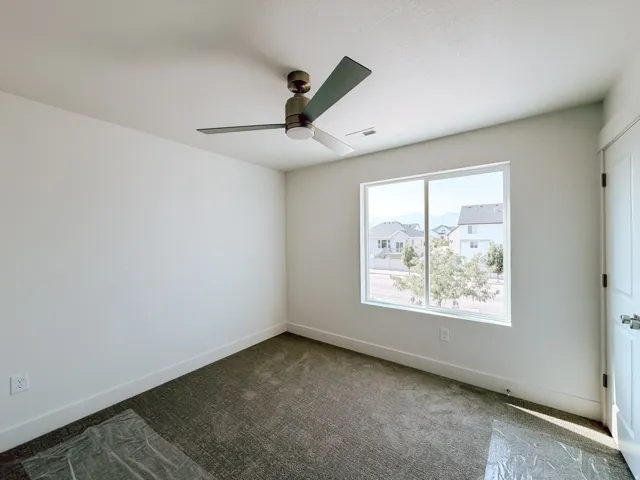 Window with white frame, dark gray carpet, white walls, and a ceiling fan