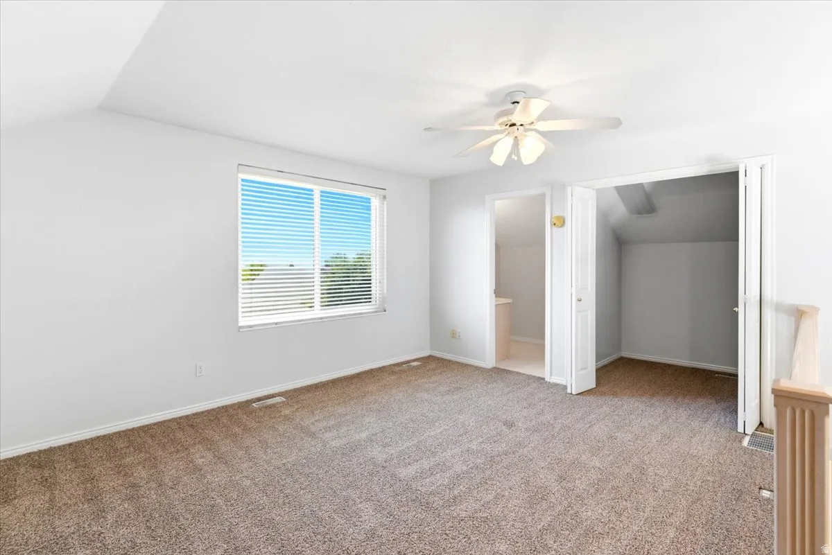Spacious loft room featuring neutral carpeting, half bath, walk in closet and a ceiling fan. Listed at 3rd bedroom.