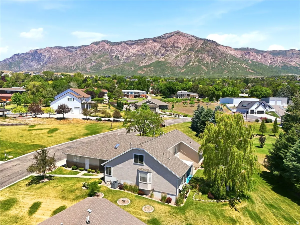 Expansive property featuring a contemporary residence with a bay window, mature trees, and a mountain backdrop