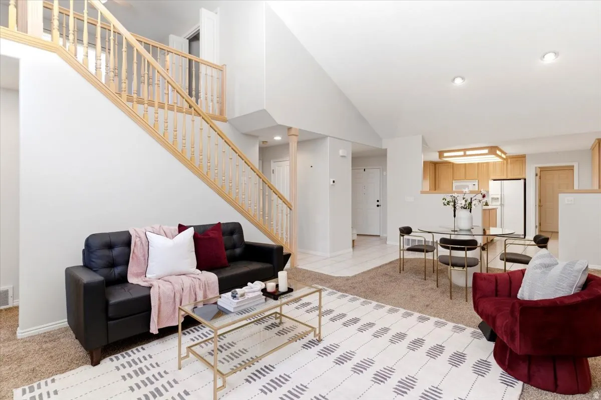 Vaulted ceiling living area with a staircase featuring wood balusters and a wood handrail