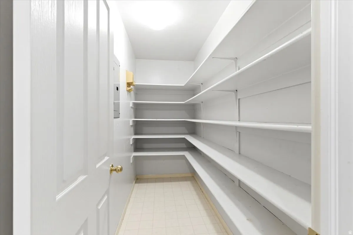 Spacious pantry featuring extensive white shelving, recessed lighting, and light-toned flooring
