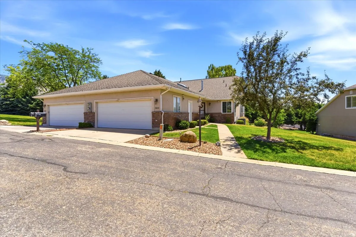 Stucco exterior property featuring a two-car garage, brick accents, a gabled roof, and a concrete driveway