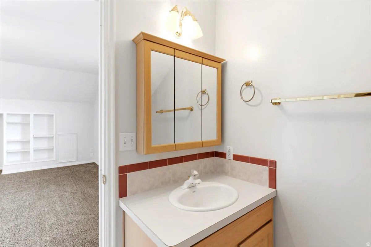 Bathroom vanity with a wood-finish cabinet, integrated sink, and laminate countertop featuring a tiled backsplash