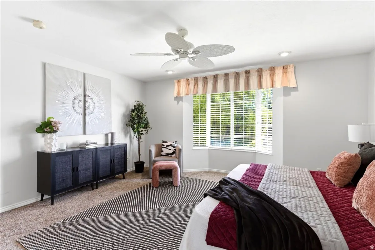Primary bedroom featuring a ceiling fan with integrated lighting, recessed lighting, and a bay window with blinds