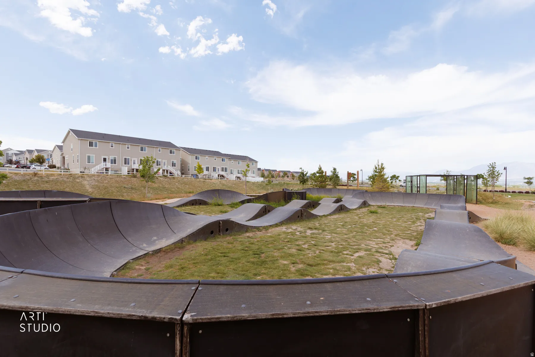 Outdoor pump track with undulating features set against a backdrop of distant mountains