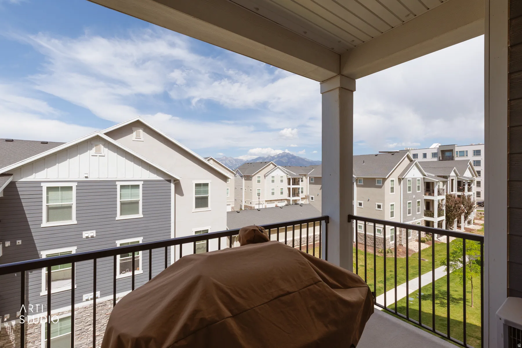 Private balcony with black metal railings, offering mountain and neighborhood scenery