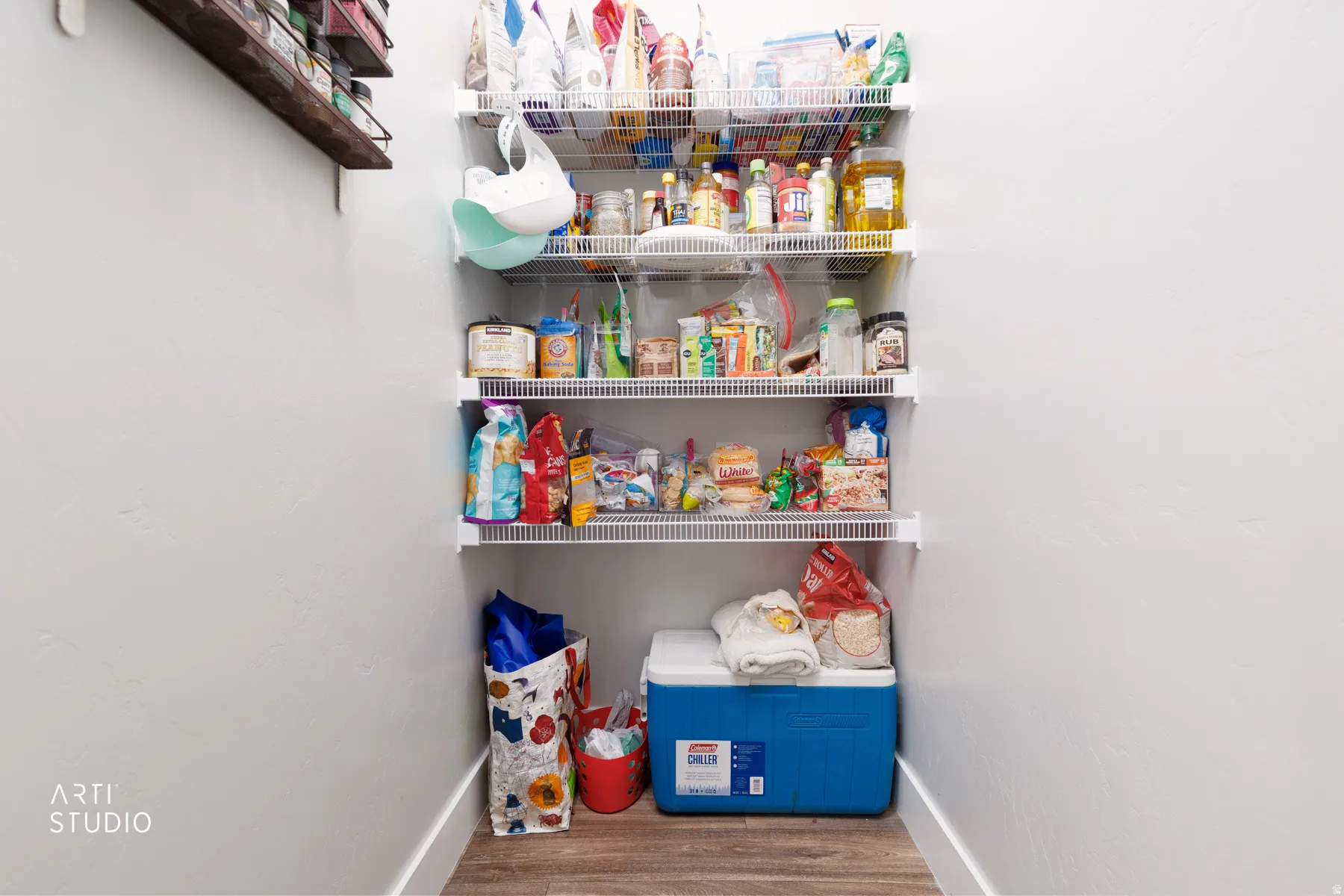 Pantry featuring multiple levels of wire shelving and wood-finish flooring
