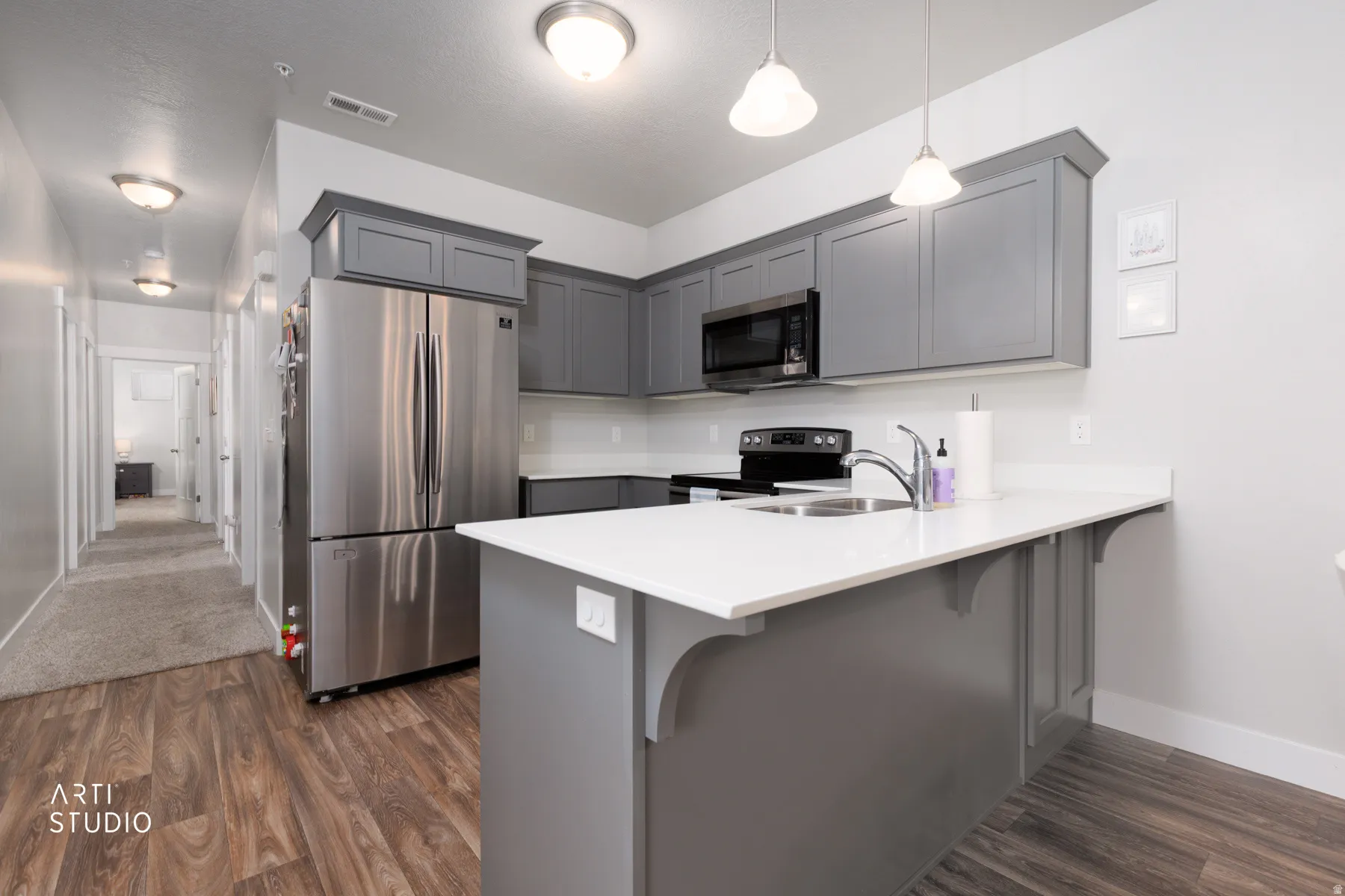 Contemporary kitchen featuring gray cabinetry, a stainless steel refrigerator, and a built-in microwave
