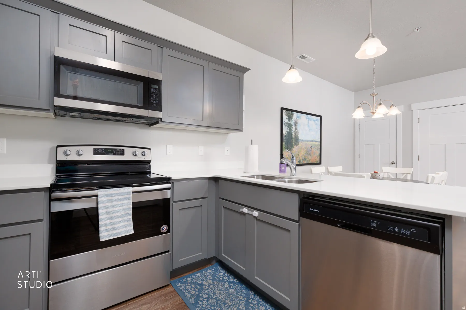 Kitchen featuring gray shaker-style cabinetry, white quartz countertops, stainless steel appliances, and wood-finish flooring