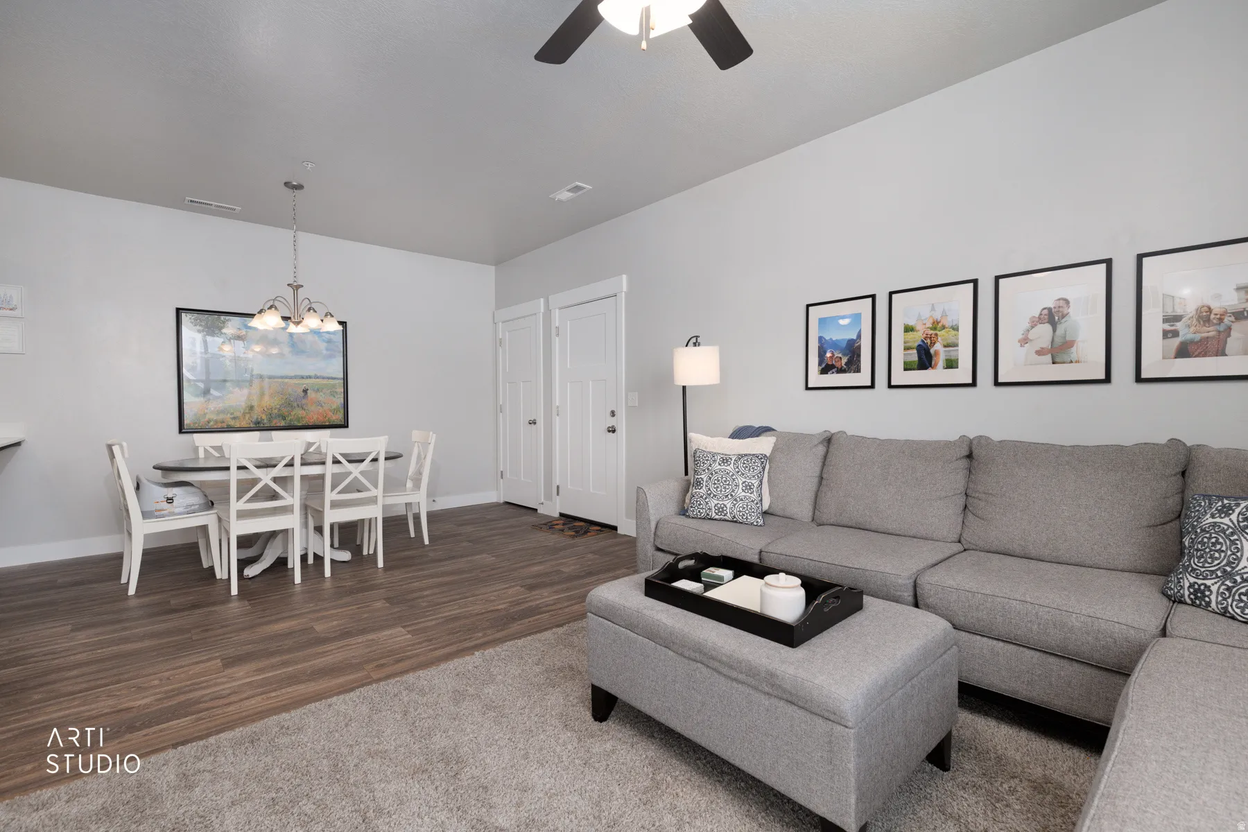 Open-concept living area featuring wood-finish flooring, light grey carpeting, and white baseboards