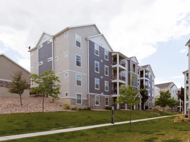 Modern multi-story condo building featuring light gray stucco and dark gray siding