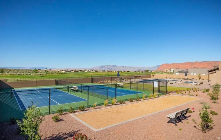 Outdoor recreation area featuring two fenced tennis courts, a bocce ball court, and a poolside patio with lounge seating
