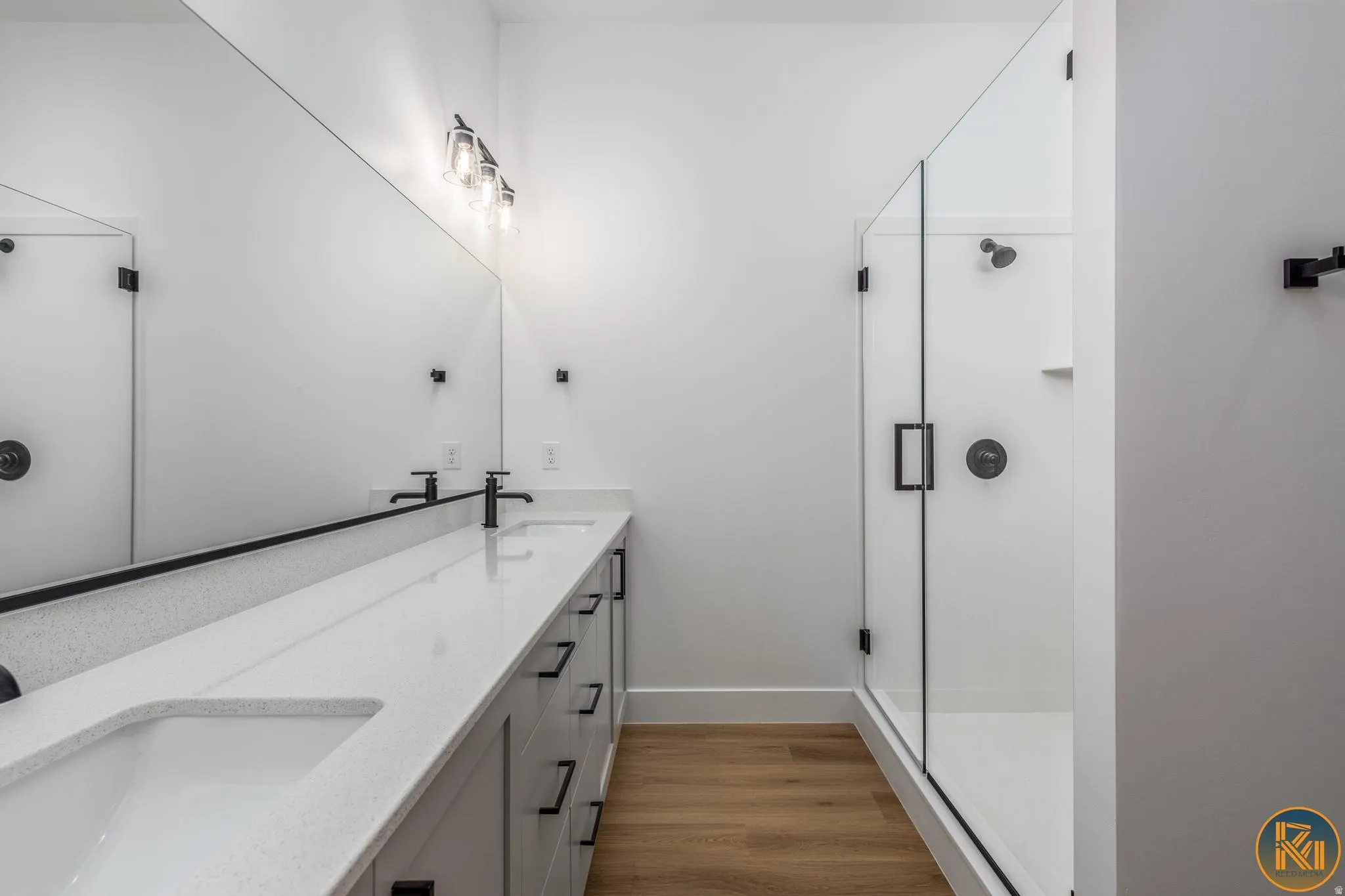 Modern bathroom featuring a dual vanity with white countertops, matte black faucets, and an oversized mirror