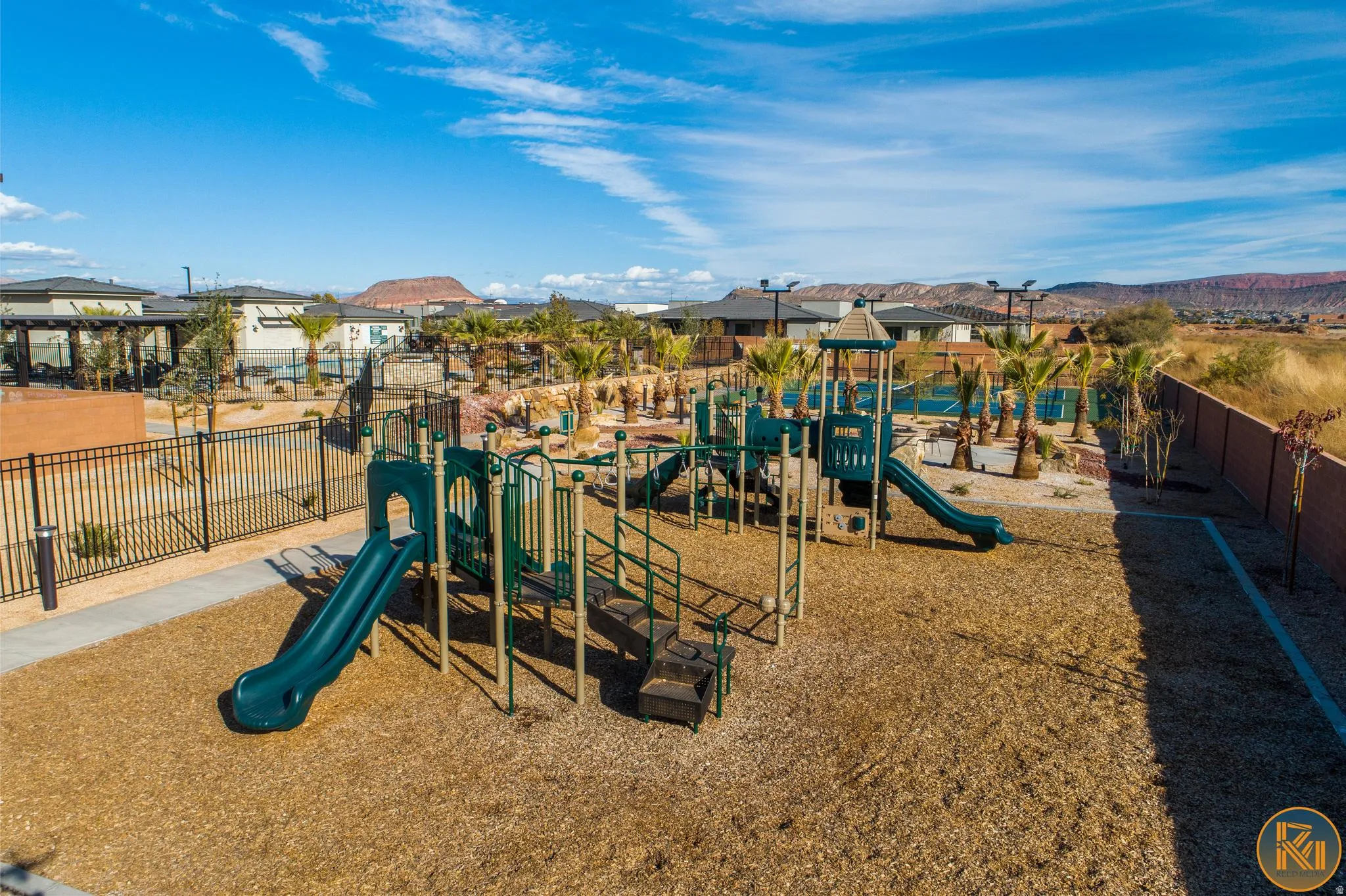 Outdoor play structure with multiple slides and climbing elements, set on a wood chip surface