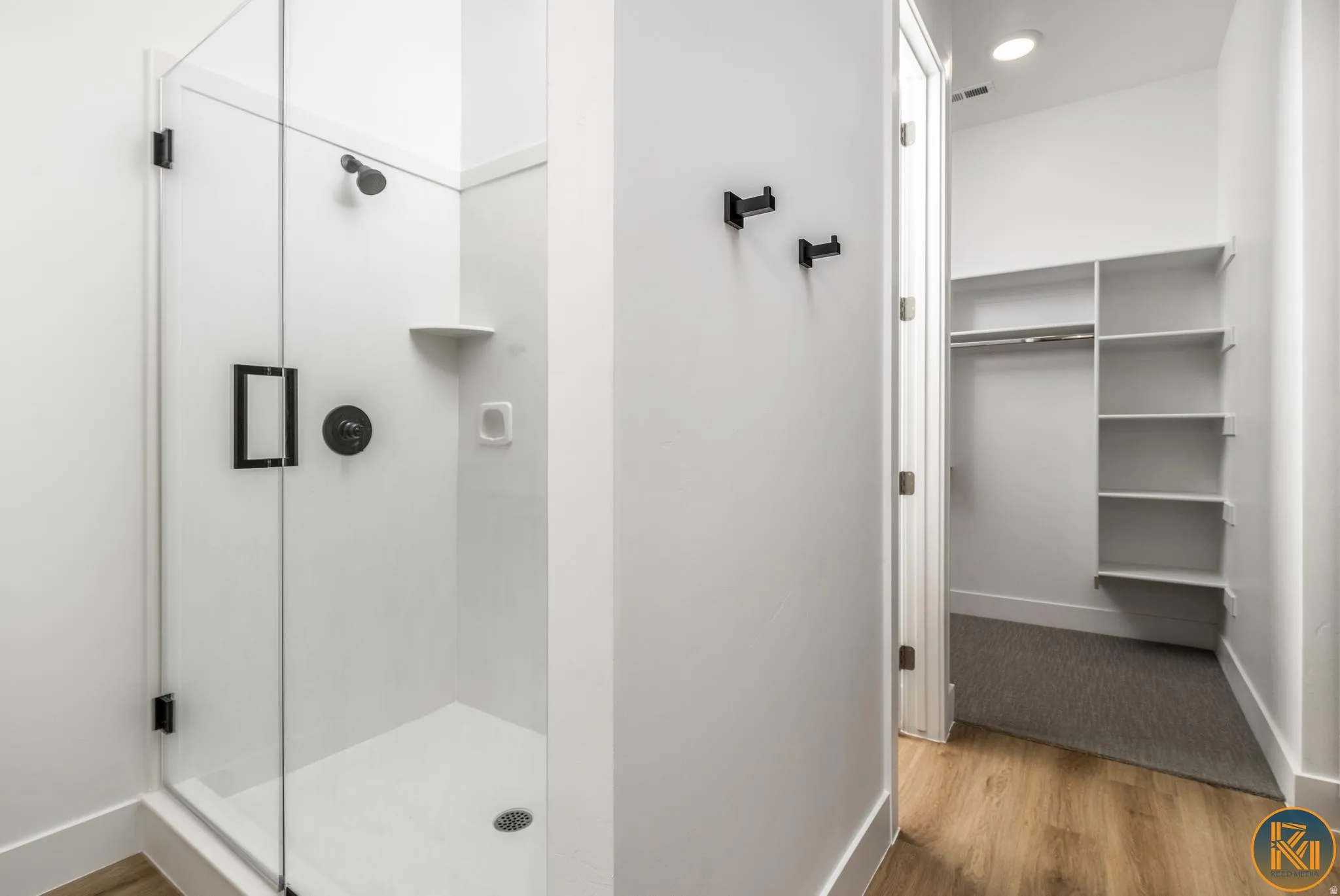 Glass-enclosed shower with matte black fixtures and an integrated shelf