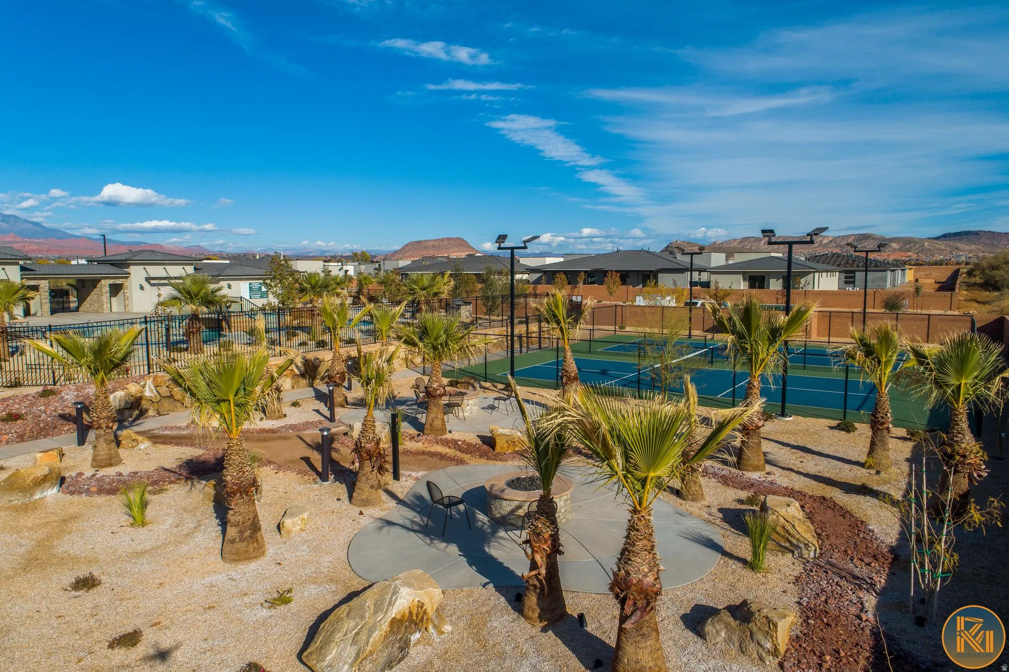 Two blue tennis courts featuring black fencing and perimeter lighting