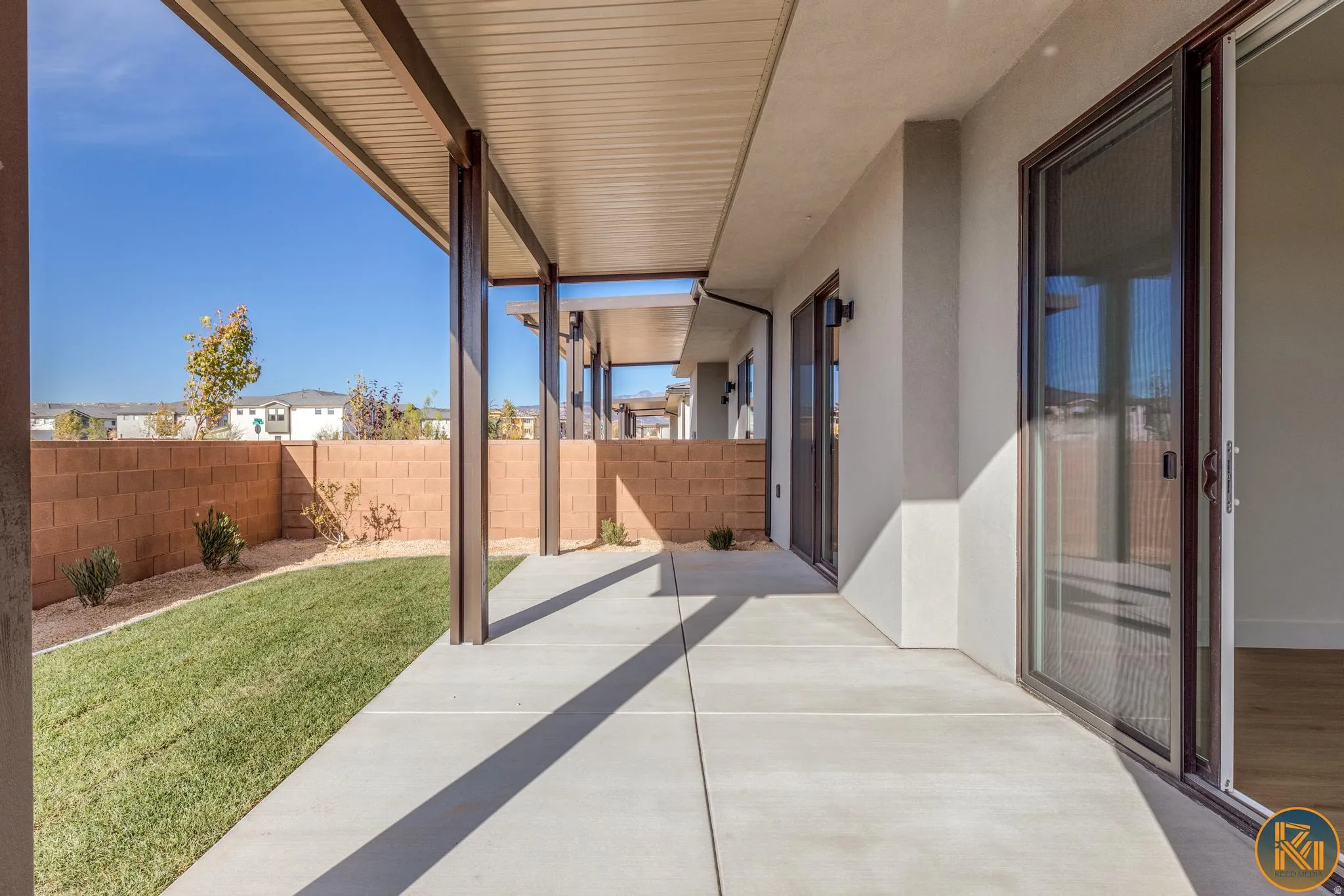 Covered patio featuring a concrete surface, a low-maintenance lawn, and a block wall perimeter