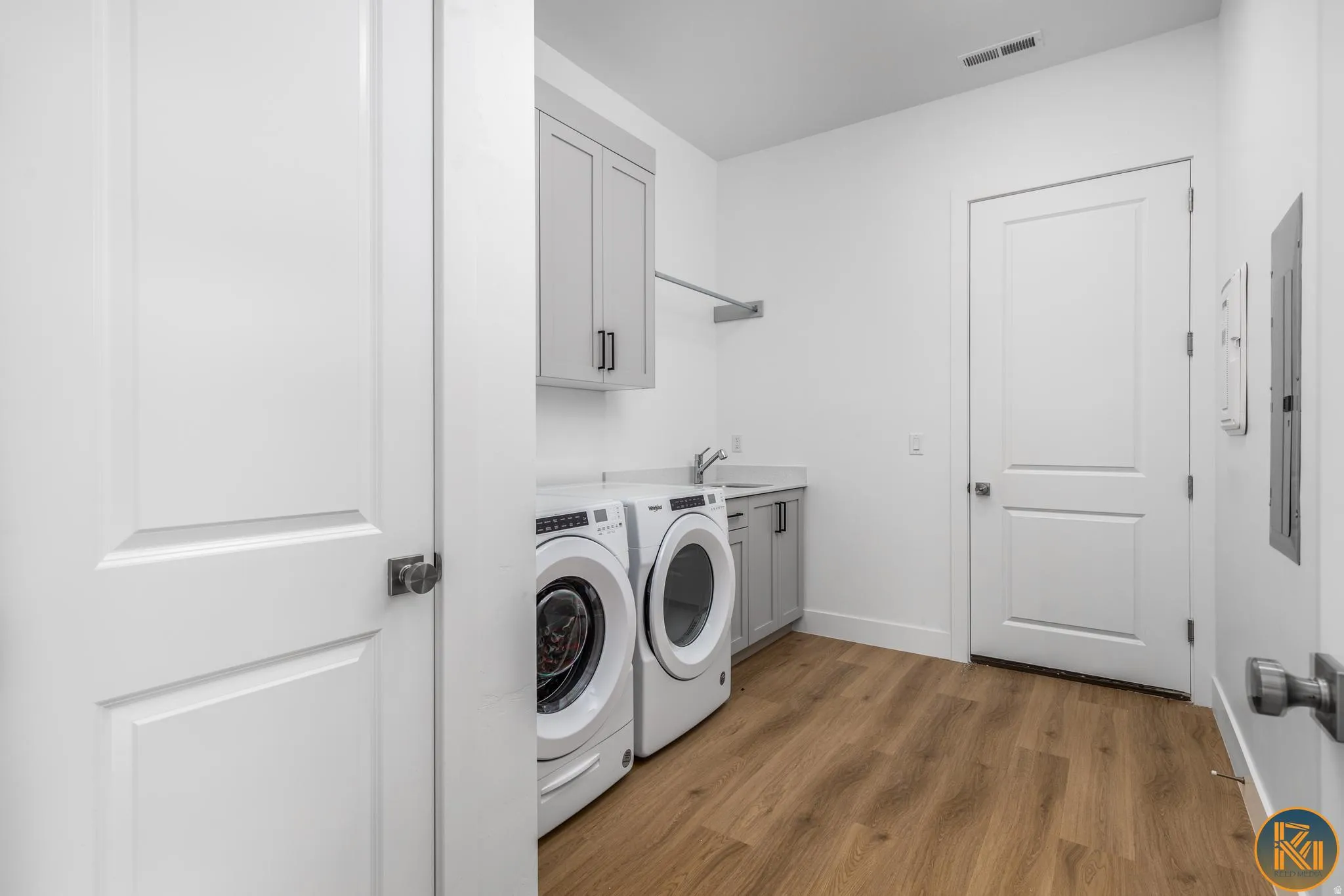 Dedicated laundry area featuring wood-finish flooring