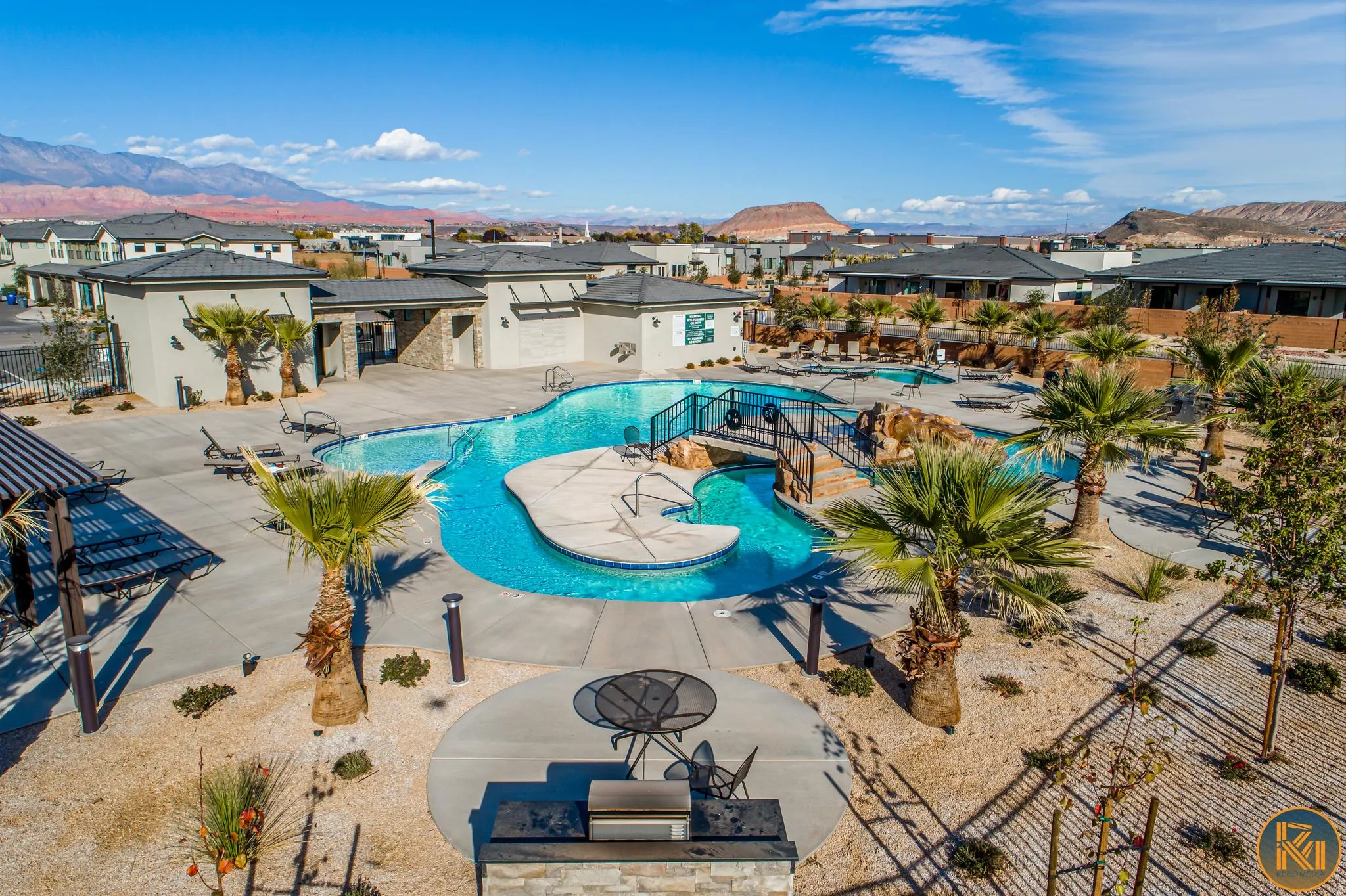 Community swimming pool with an integrated spa, surrounded by desert landscaping and mature palm trees