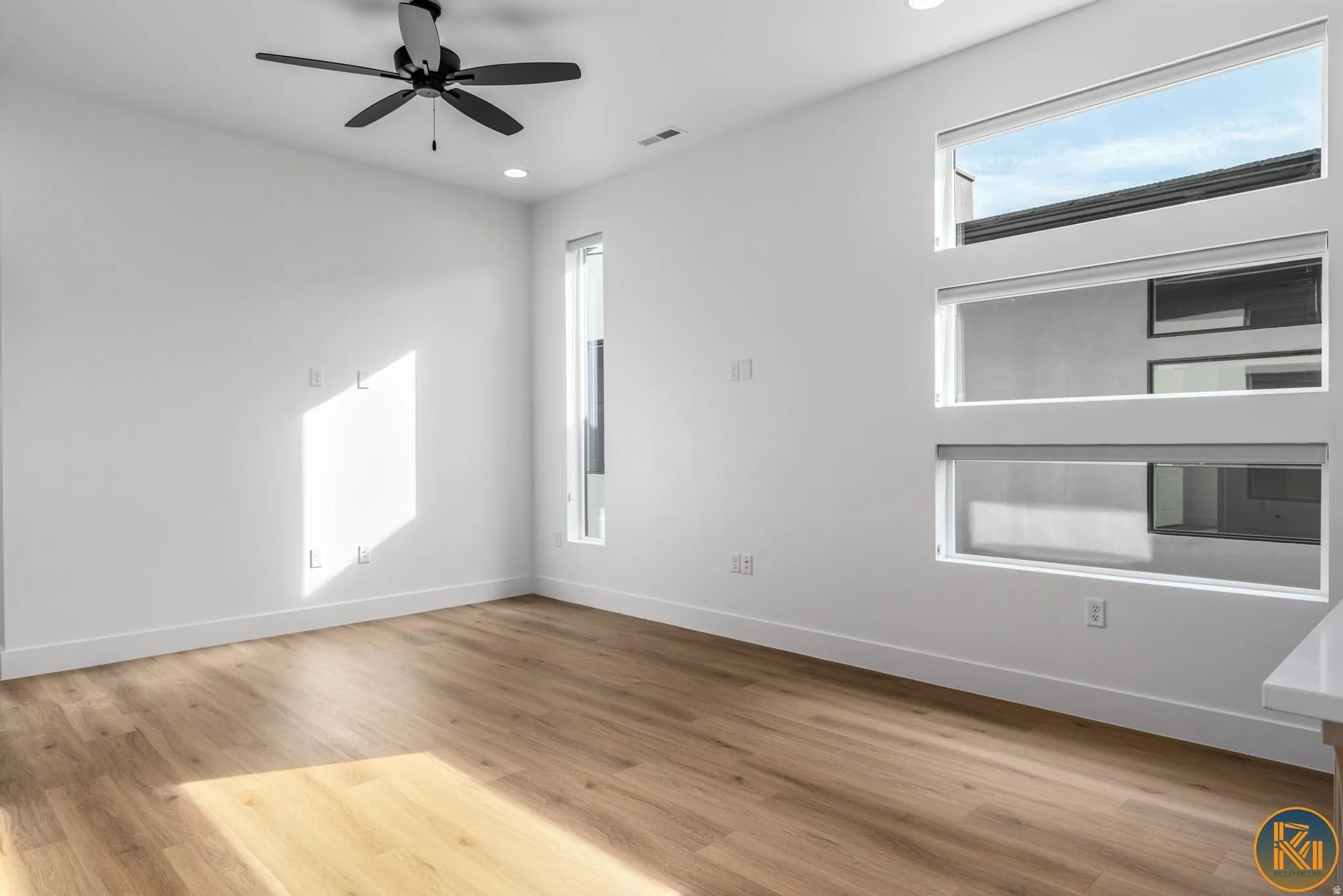Spacious room featuring wood-finish flooring, recessed lighting, and a contemporary ceiling fan