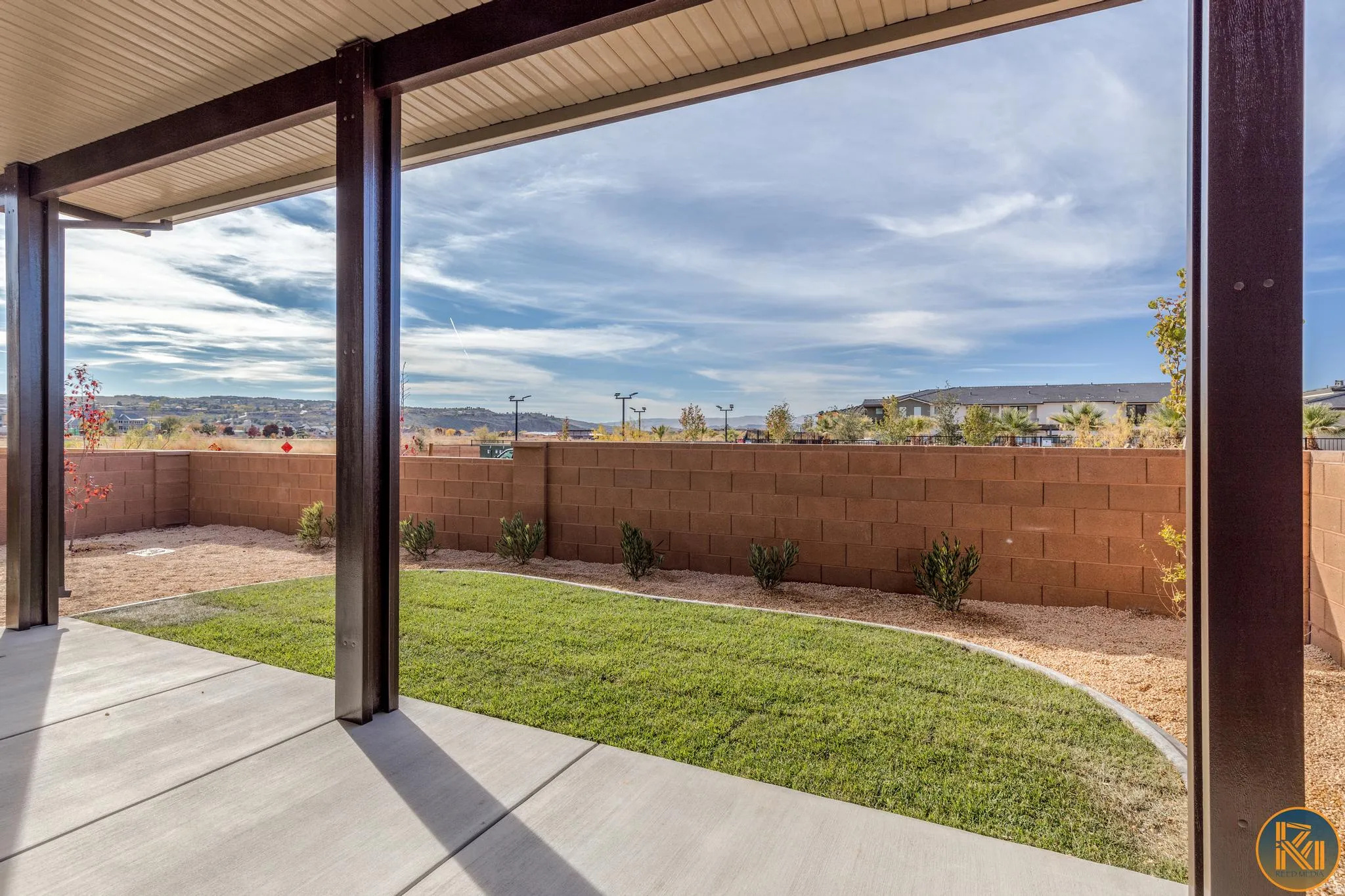 Covered patio with concrete flooring, framed by dark structural posts