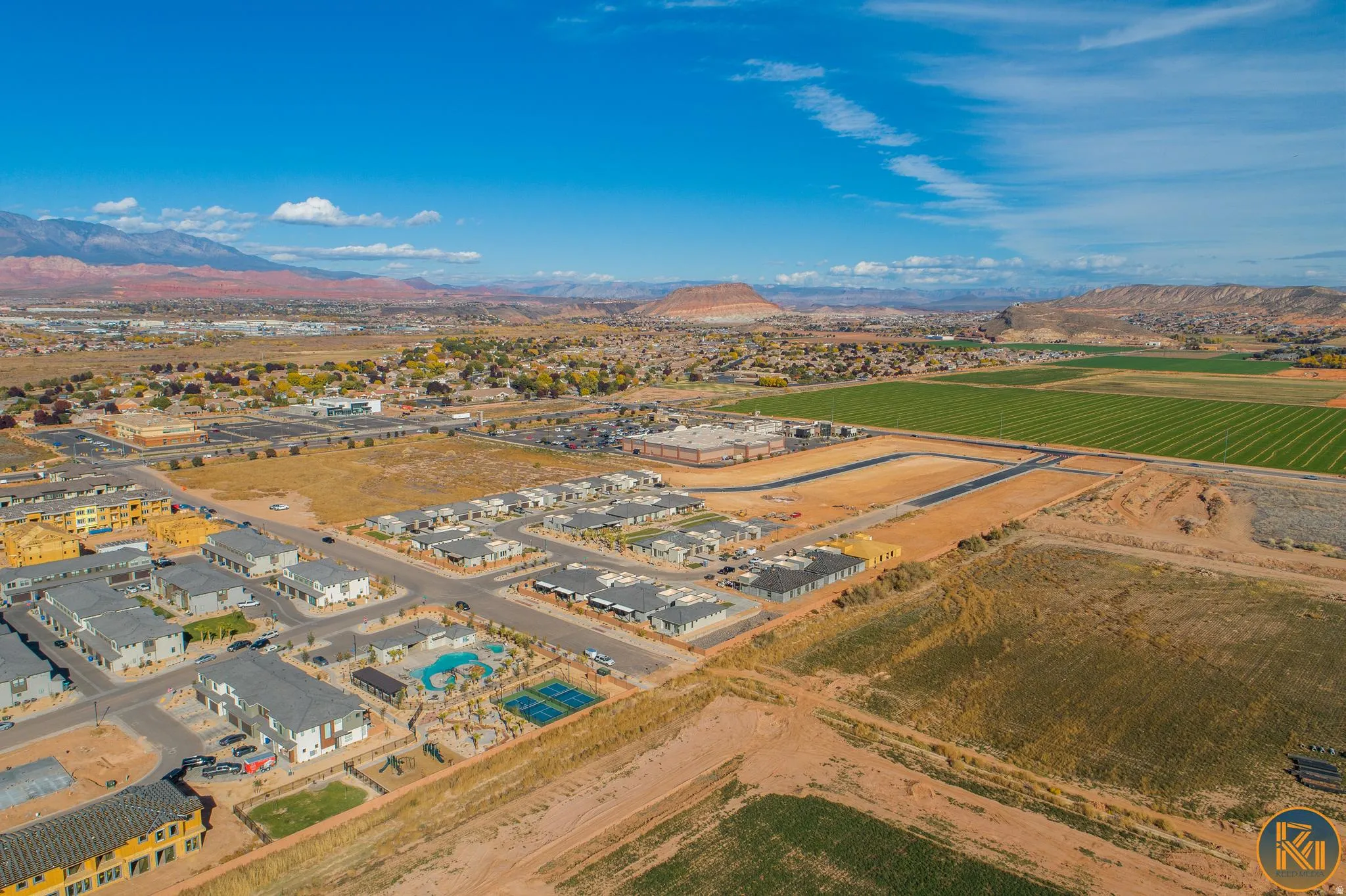 Aerial landscape showcasing diverse residential developments, agricultural fields, and distant red rock formations