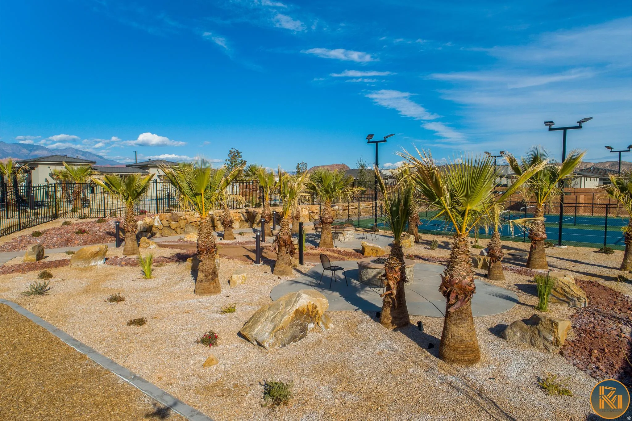 Landscaped outdoor area featuring multiple palm trees, natural rock accents, and a light-colored gravel ground cover