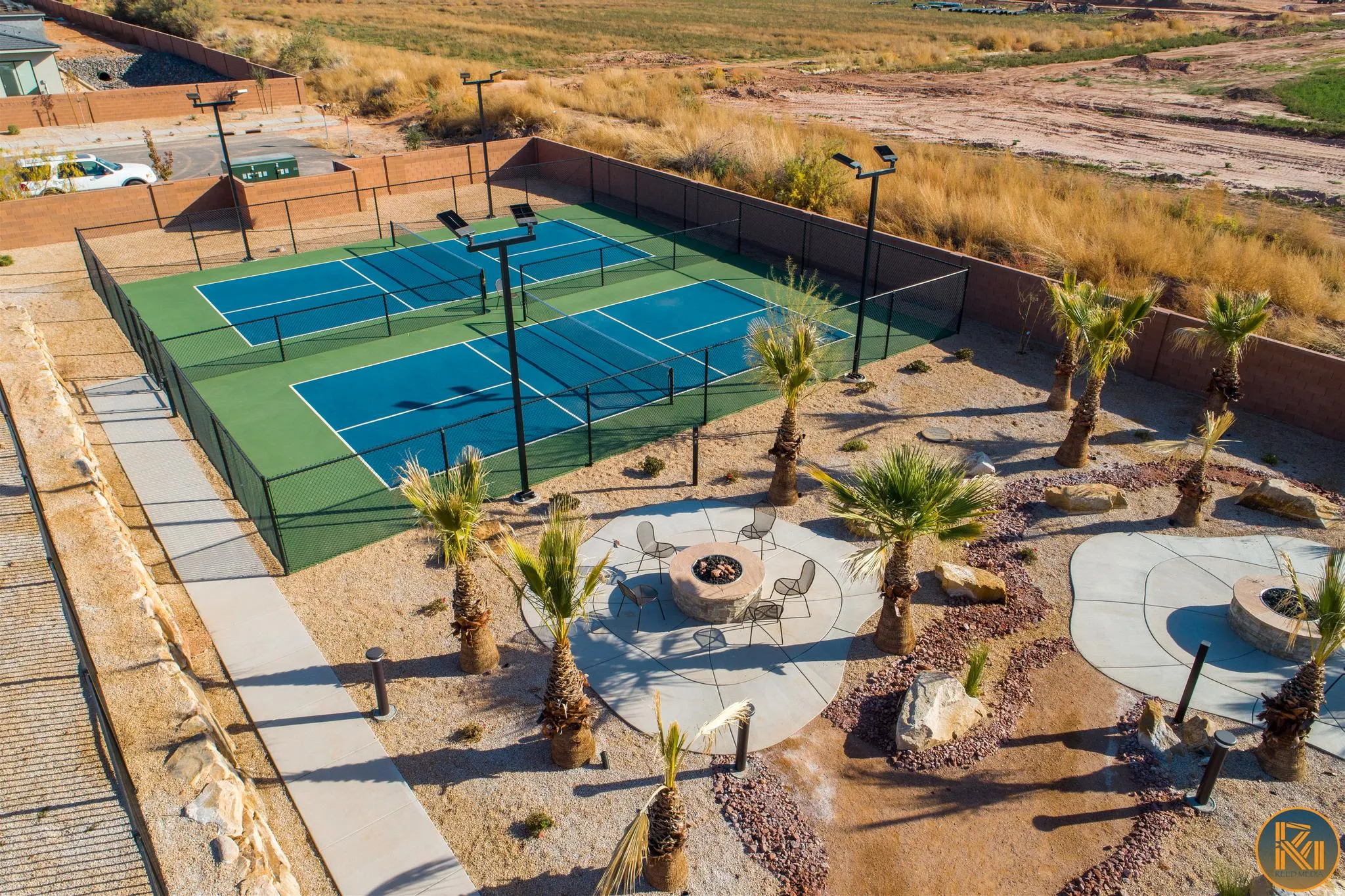 Outdoor recreational area featuring multiple courts, desert landscaping, and a fire pit