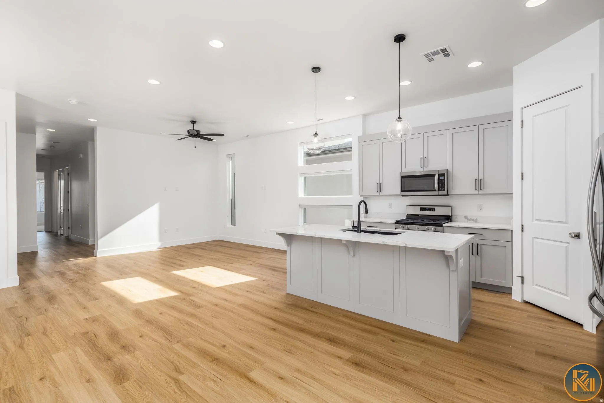 Open-concept living space featuring wood-finish flooring, recessed lighting, and a contemporary ceiling fan