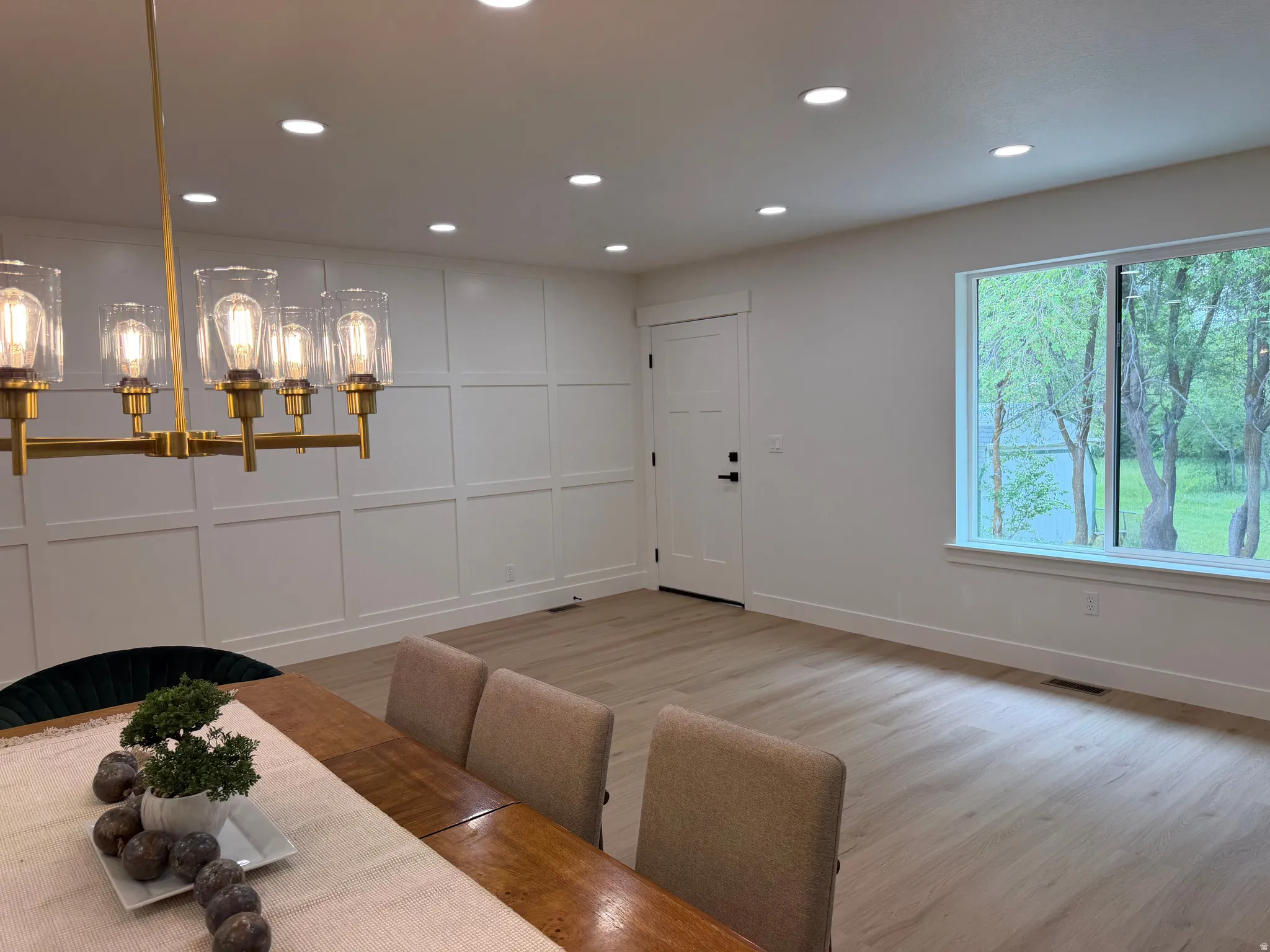 Bright interior space featuring wood-finish flooring, recessed lighting, and a modern brass chandelier with clear glass shades