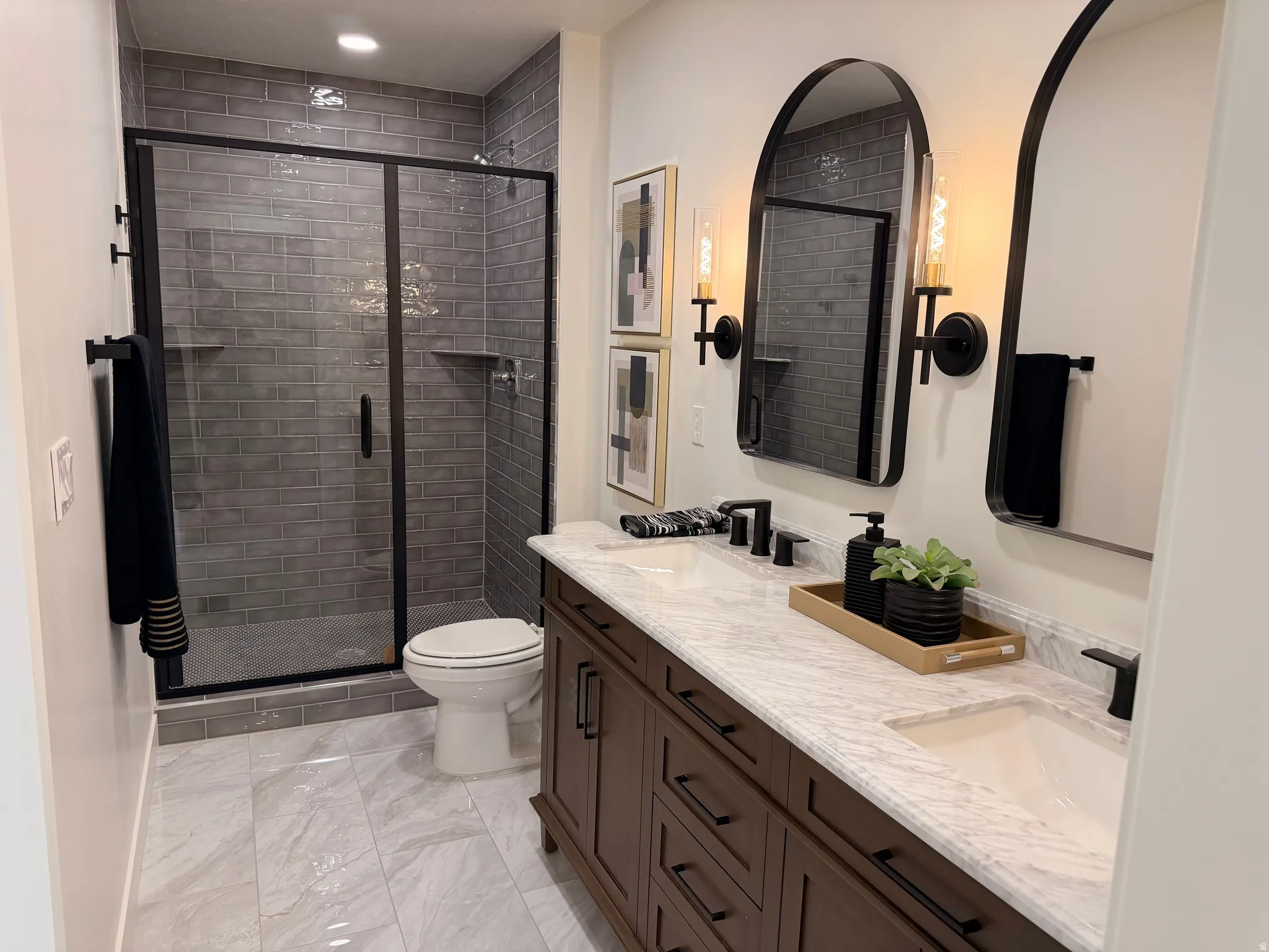 Bathroom featuring a dual vanity with a light-toned countertop, dark wood-finish cabinetry, and black fixtures