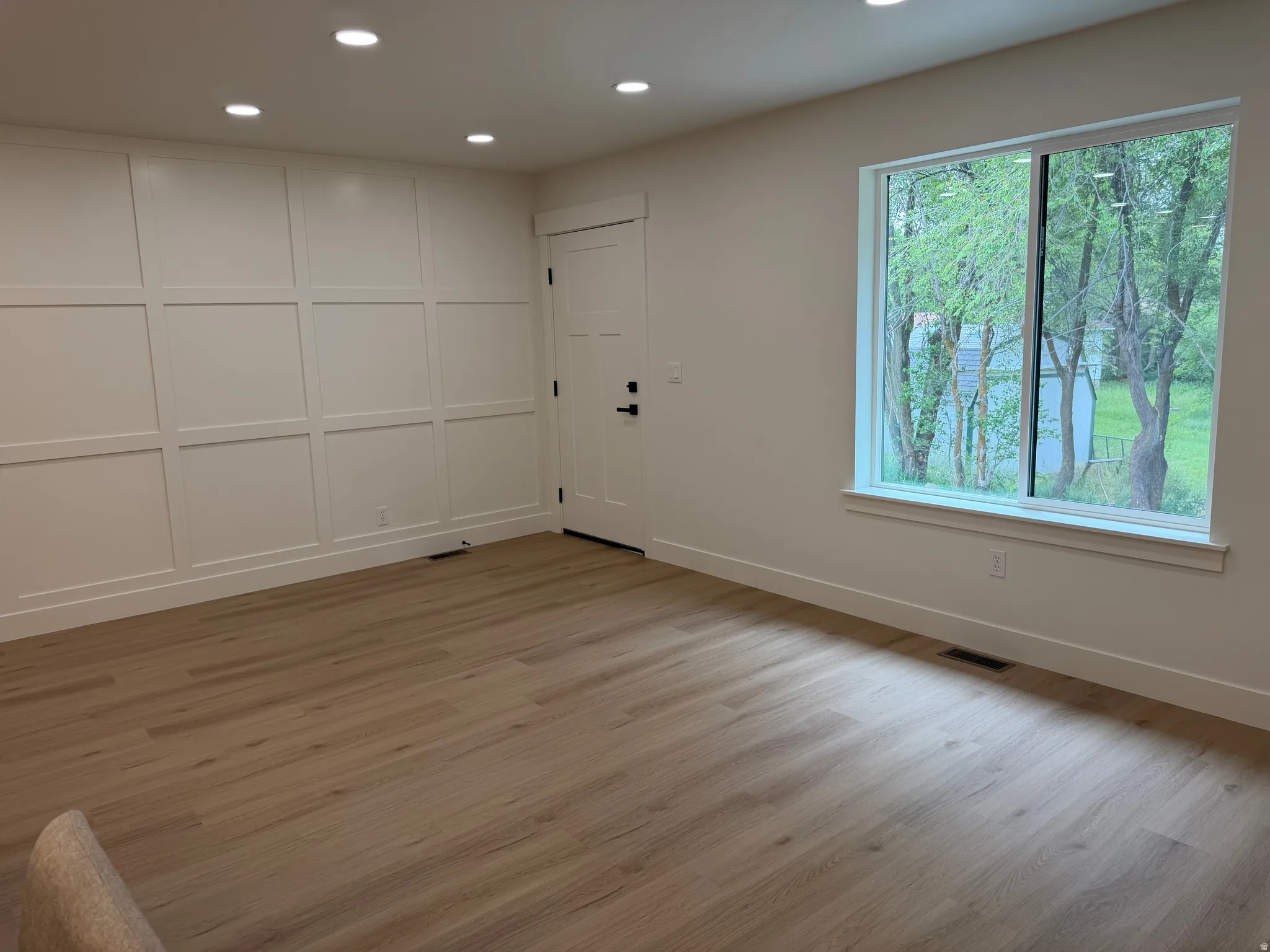 Bright interior space featuring a grid accent wall, recessed lighting, and light wood-finish flooring